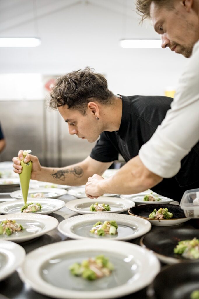 Chefs plating gourmet dishes meticulously.
